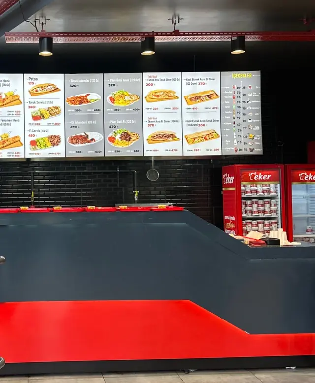 The red and black self-service counter under the lit menu board